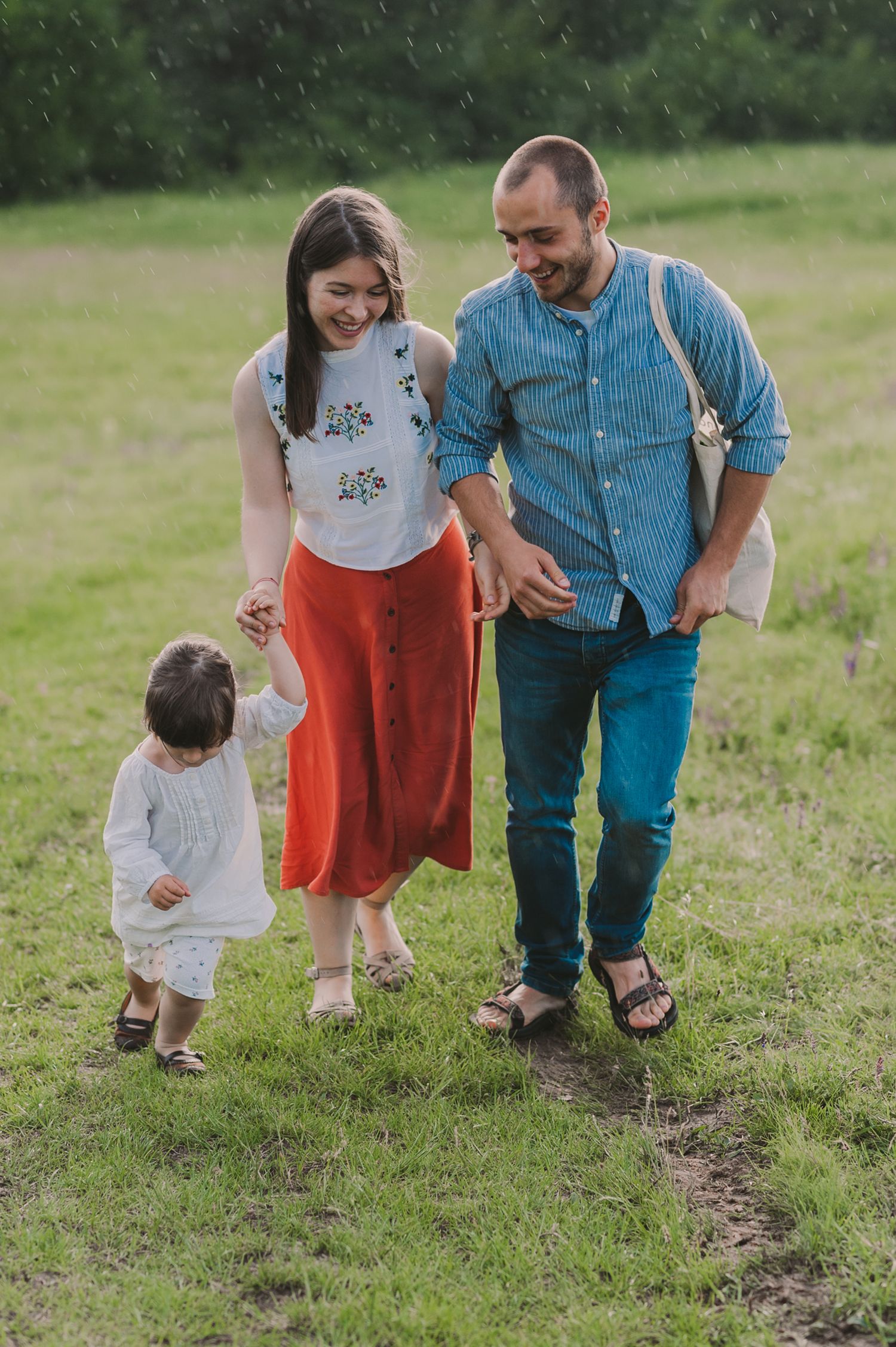 Family members walking together on a grassy path while enjoying an outdoor adventure.