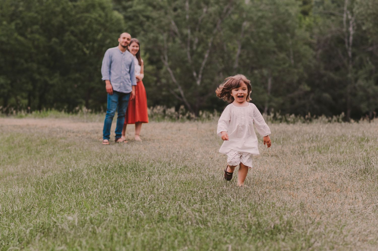 A family enjoys a playful moment together in a scenic meadow.