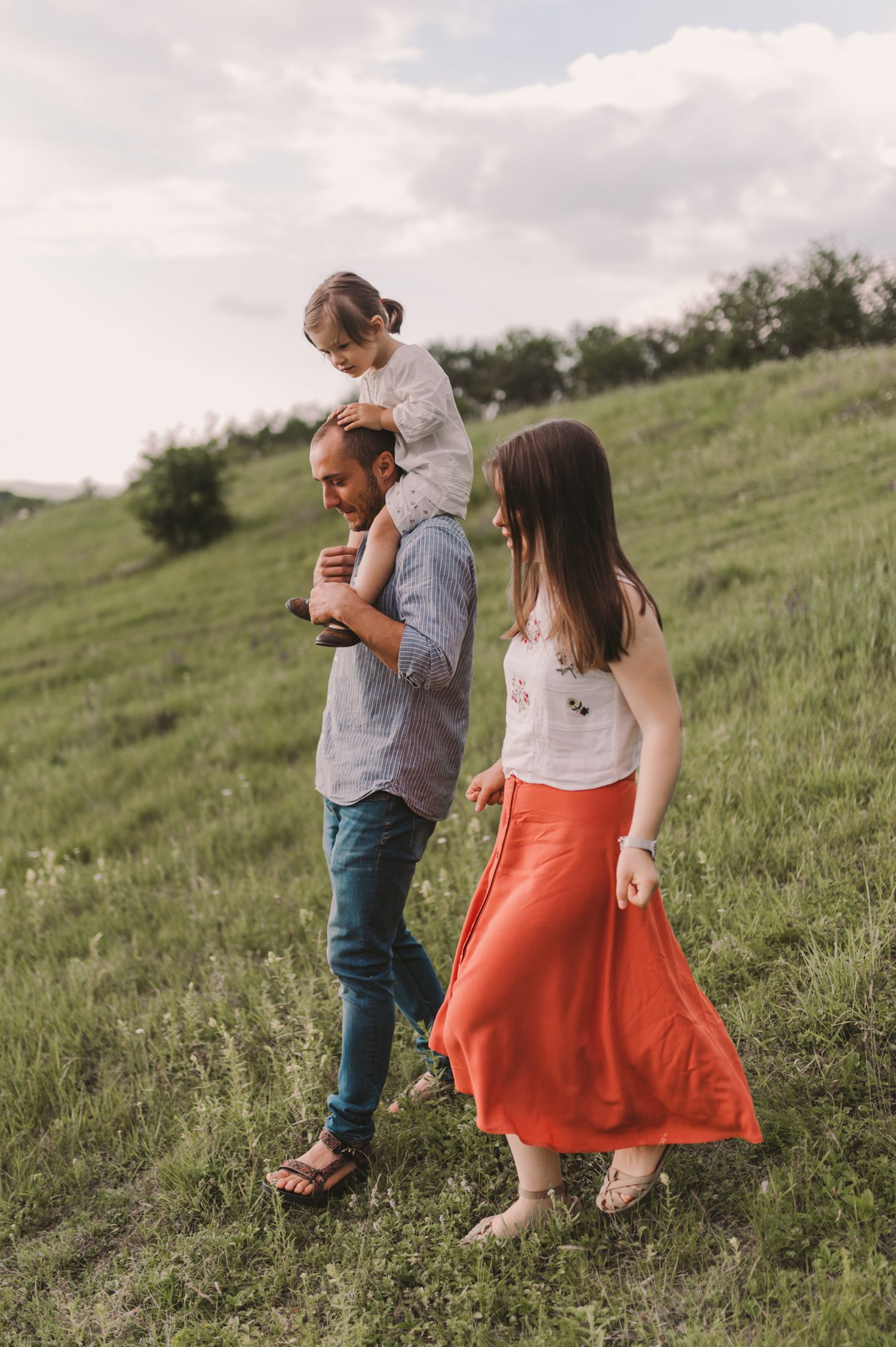 People walking together through tall grass on a gentle hillside.