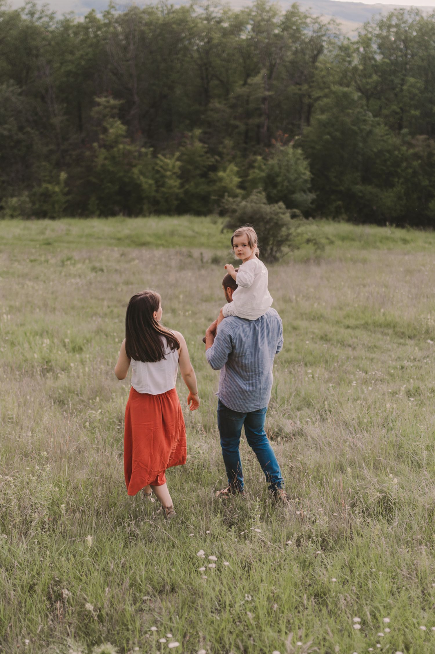 People walking together through a scenic meadow with trees in the background.