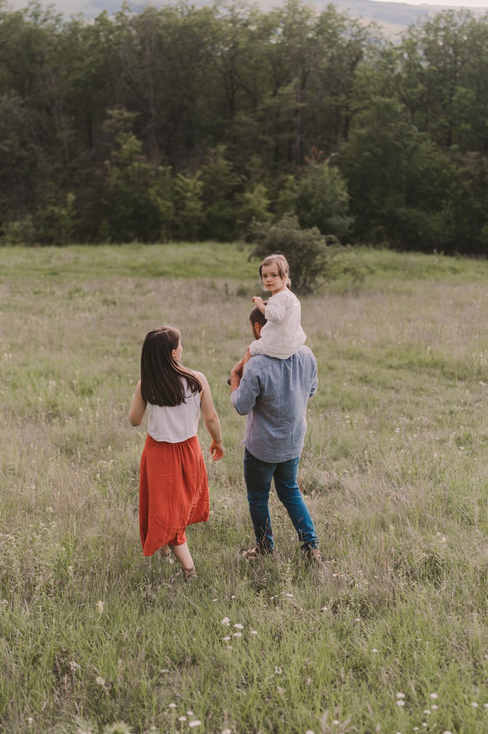 People walking together through a scenic meadow with trees in the background.