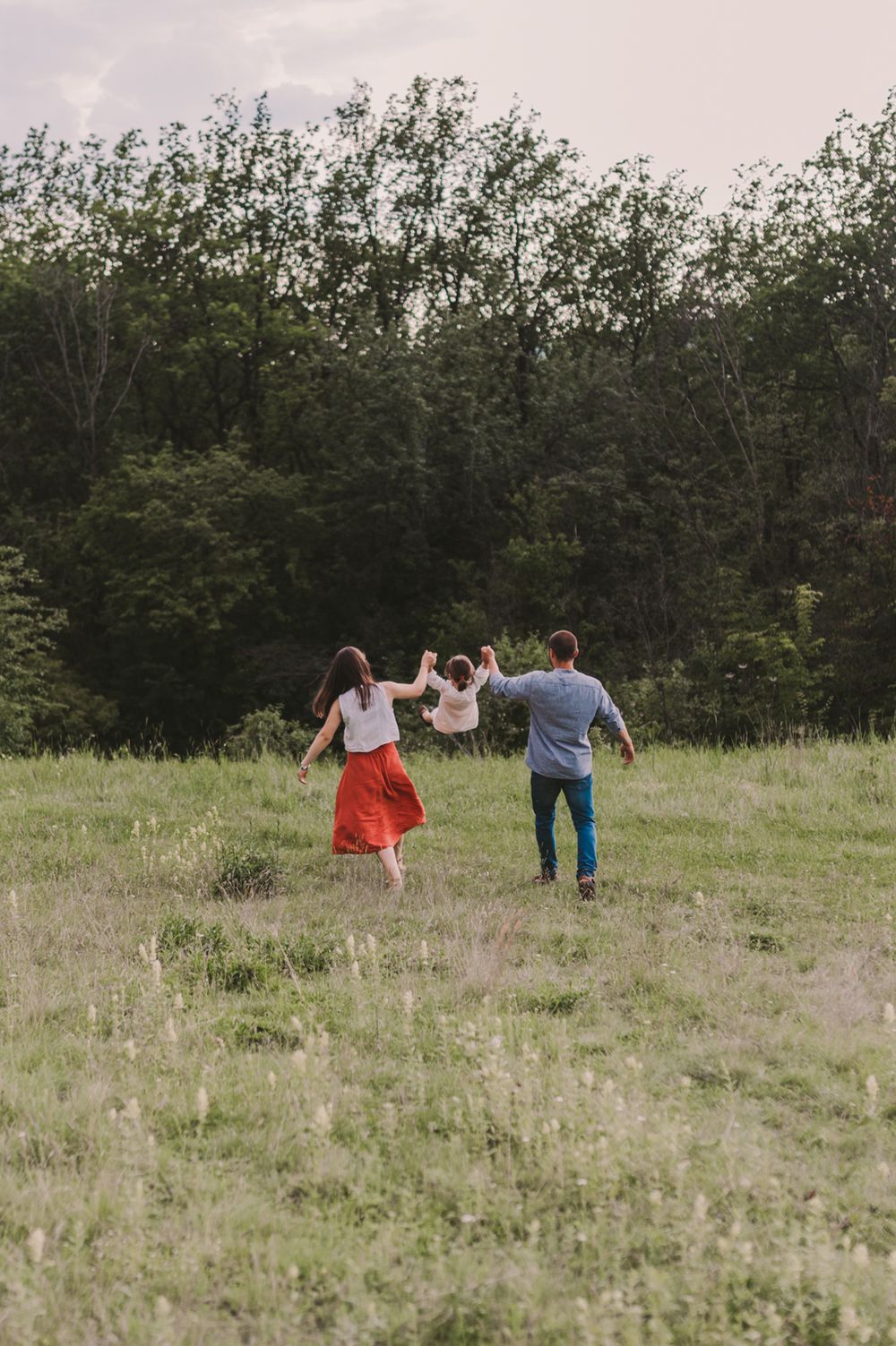 A group explores a scenic meadow surrounded by trees on a cloudy day.