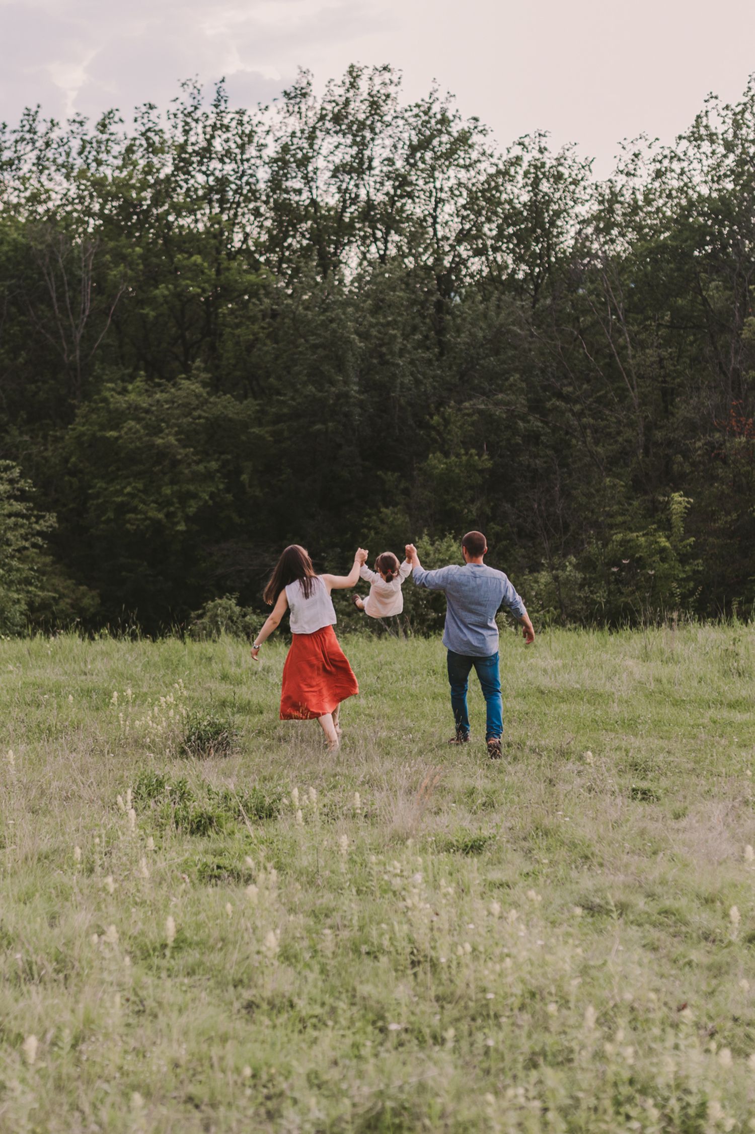 A group explores a scenic meadow surrounded by trees on a cloudy day.