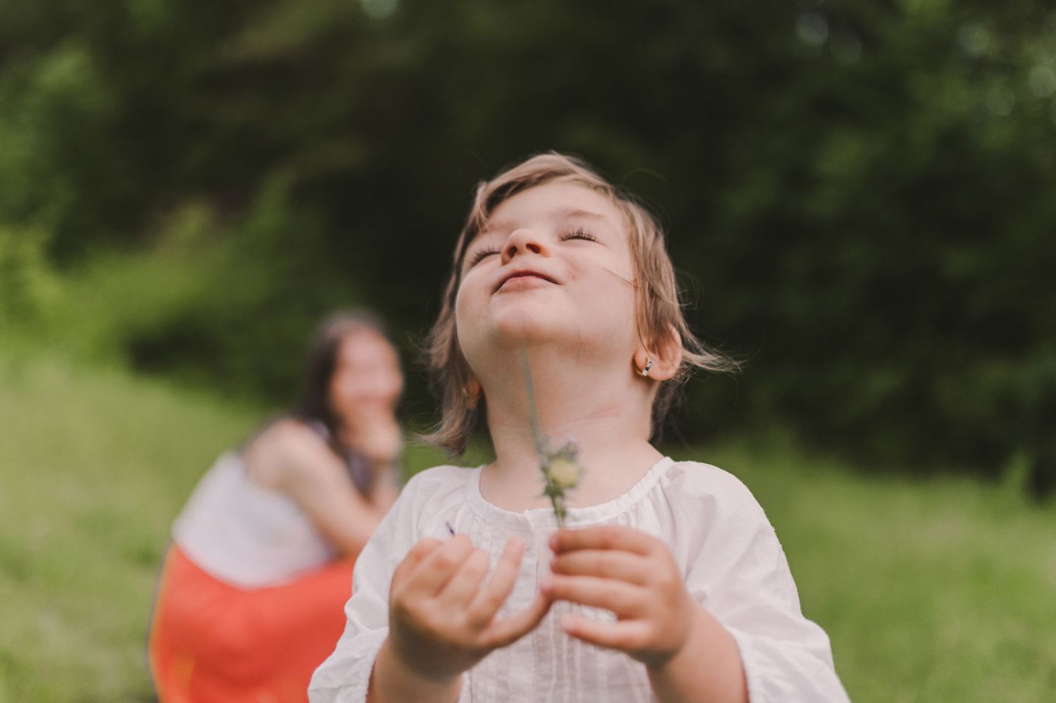 Family enjoying a playful moment together in a grassy meadow during a summer photoshoot.