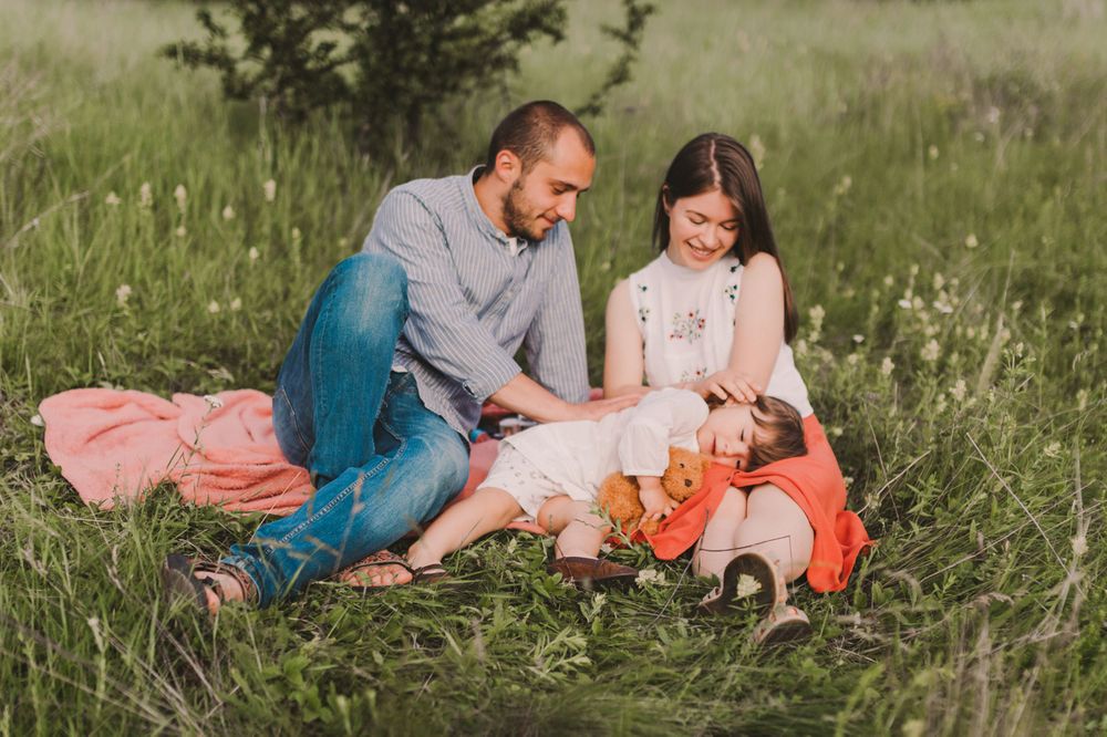 Family sitting together in a grassy field during a warm summer day.
