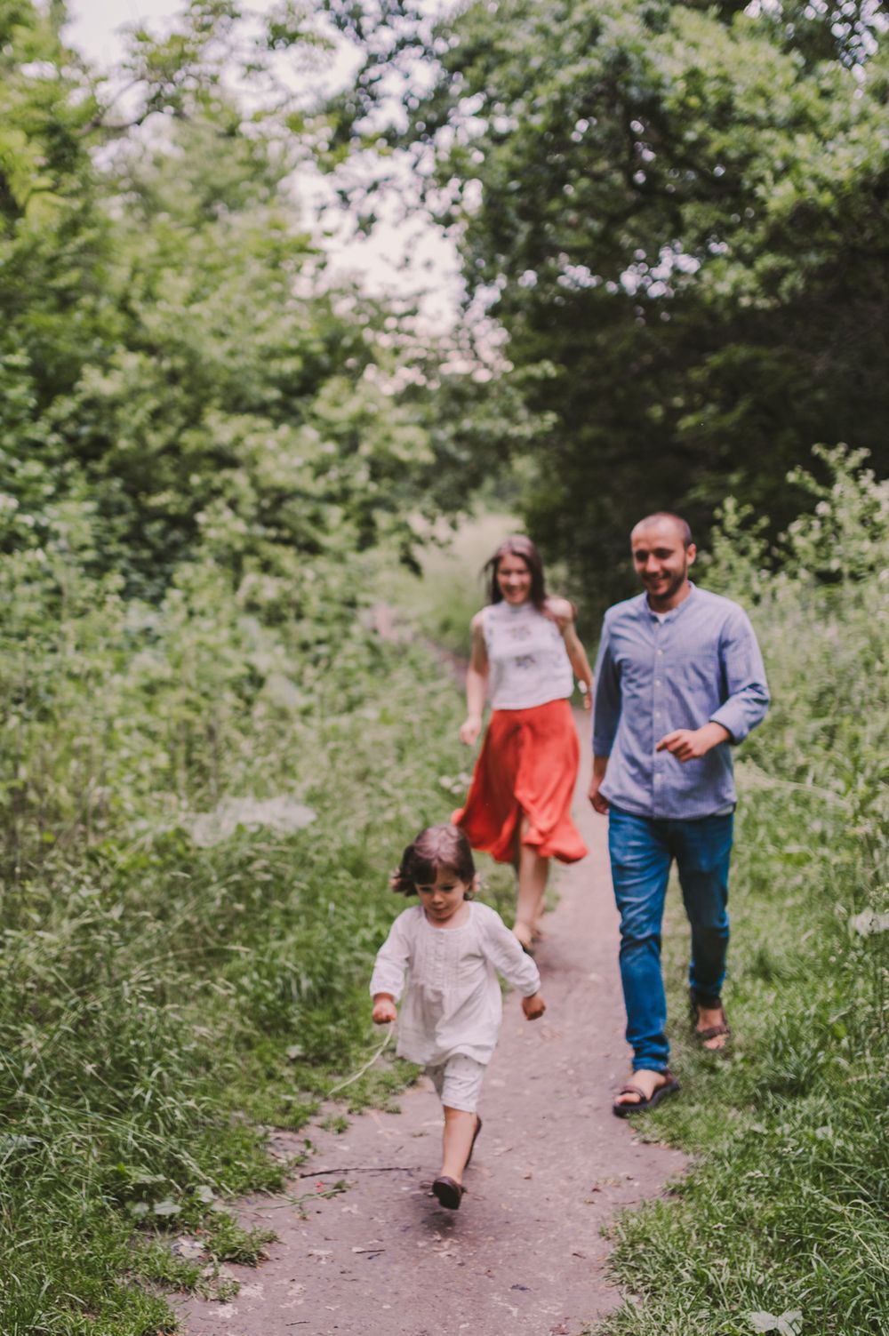 Family walking together on a winding nature trail surrounded by lush greenery.