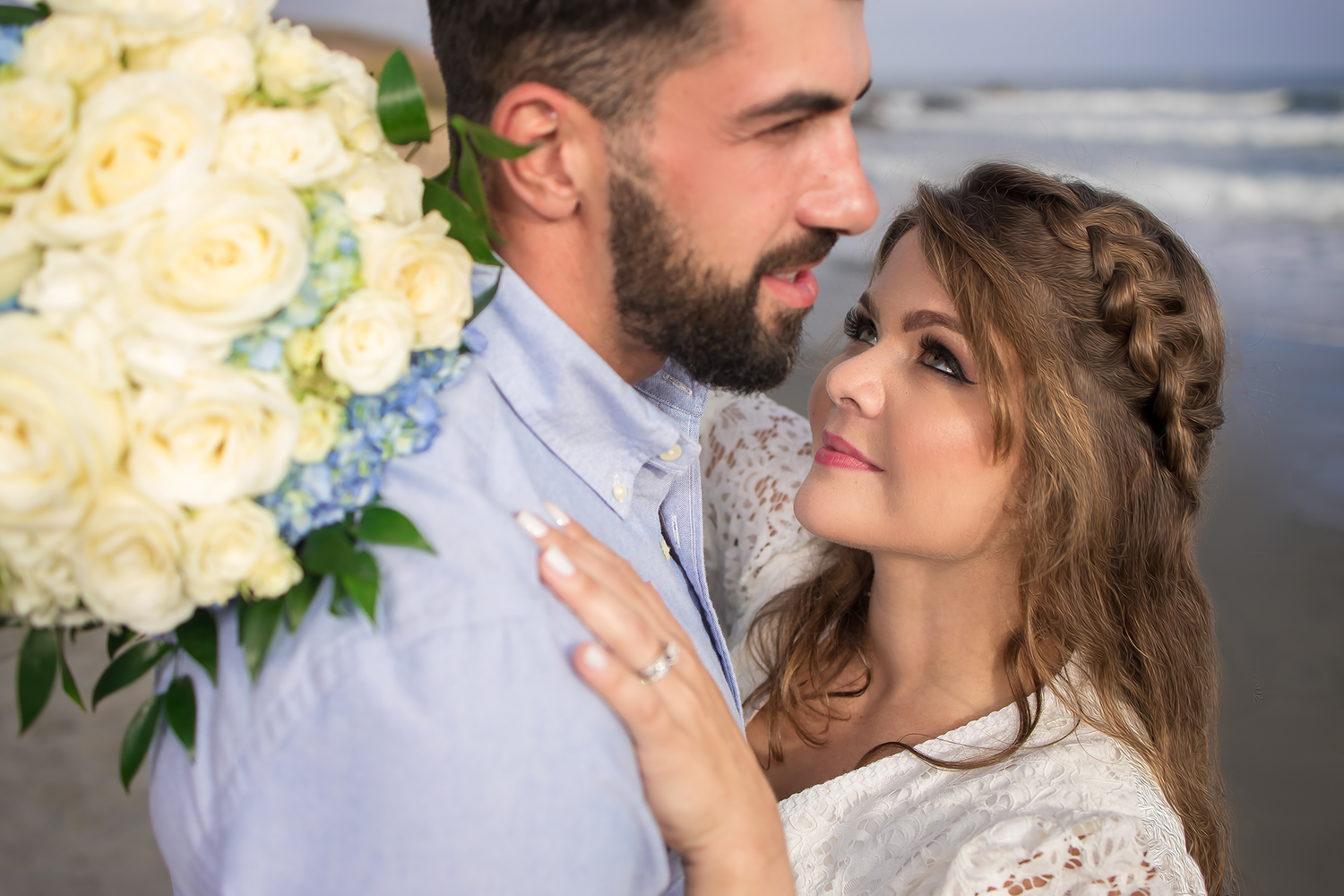 A romantic moment with white roses and ocean waves in the background.