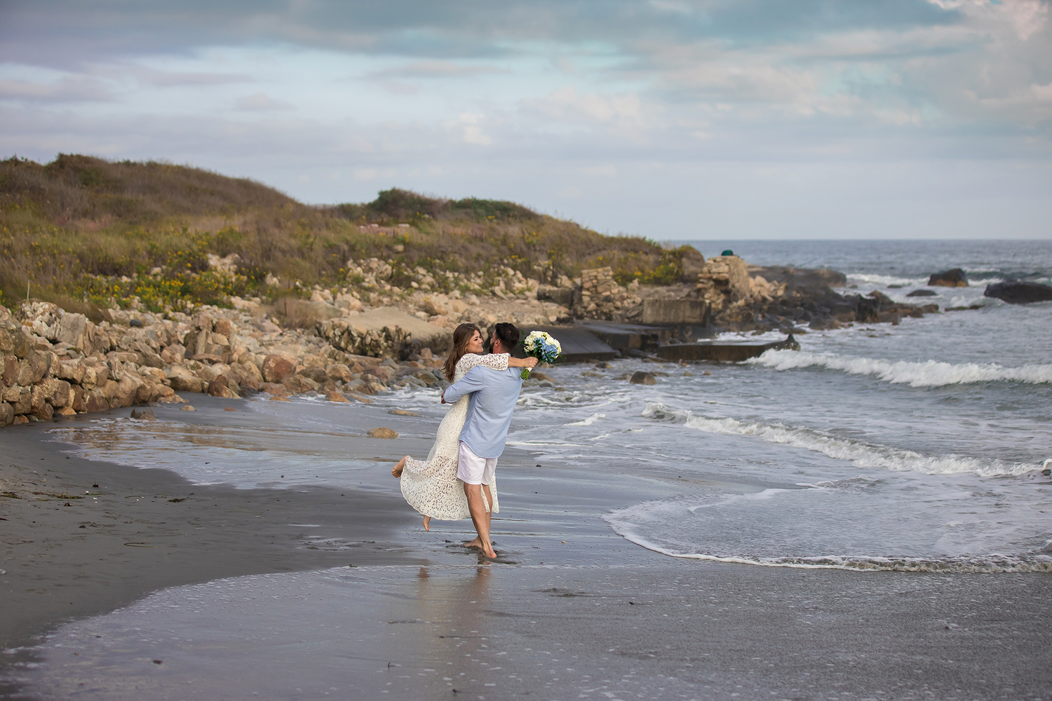 A coastal beach photoshoot with waves crashing against rocky cliffs in the background.