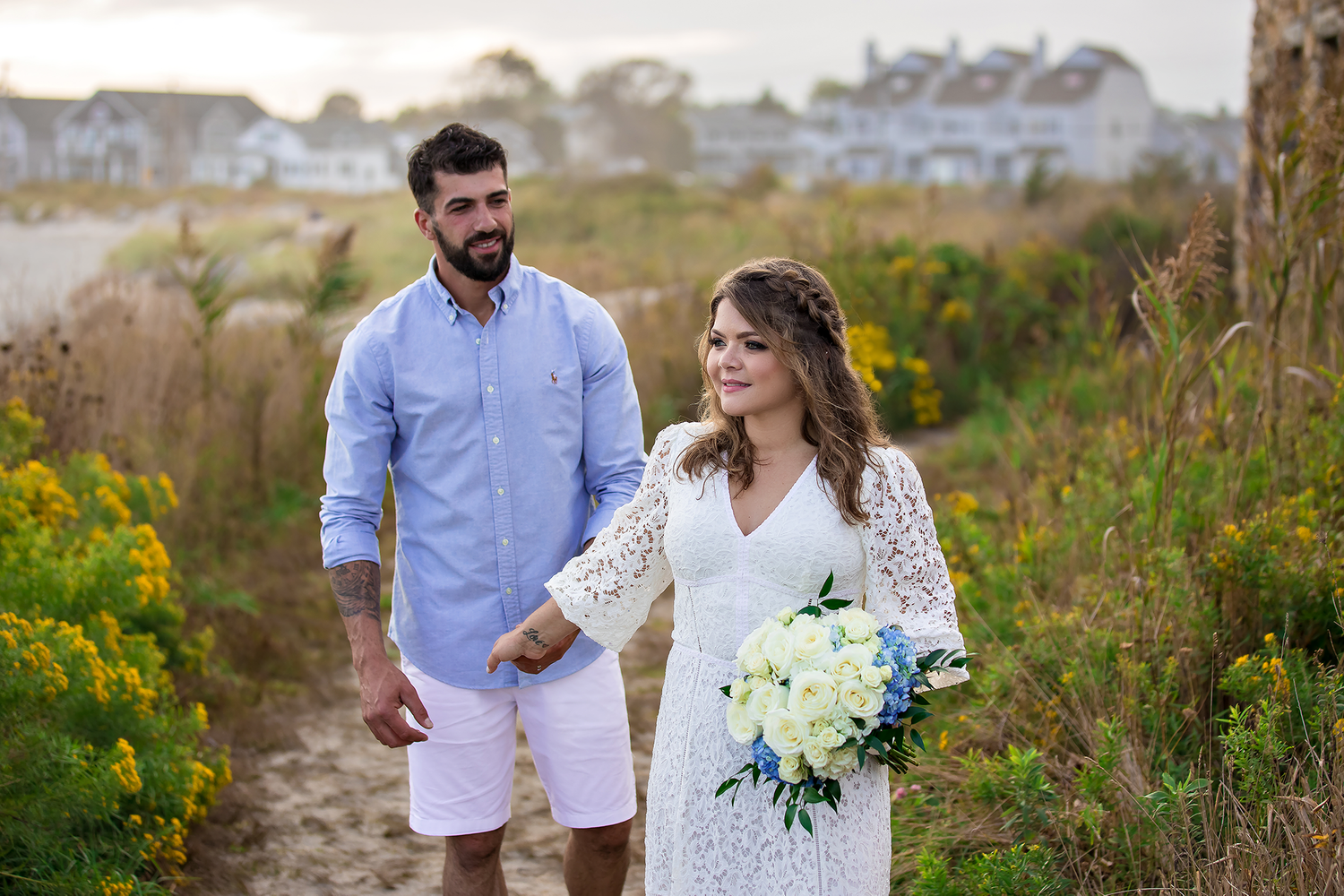 A romantic photoshoot in a field with yellow wildflowers and a white lace dress.