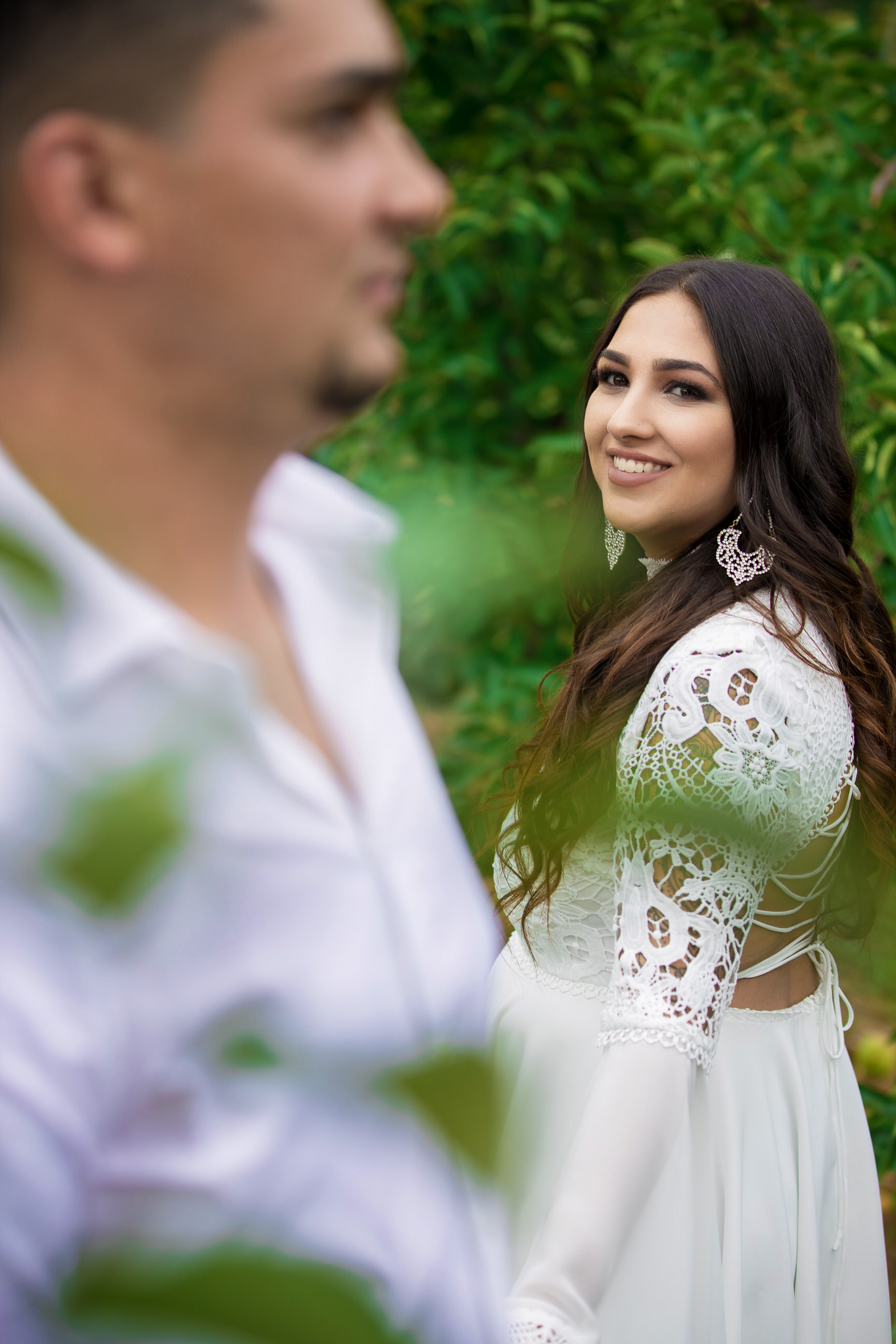 A romantic photoshoot in a lush green garden setting with white lace details.