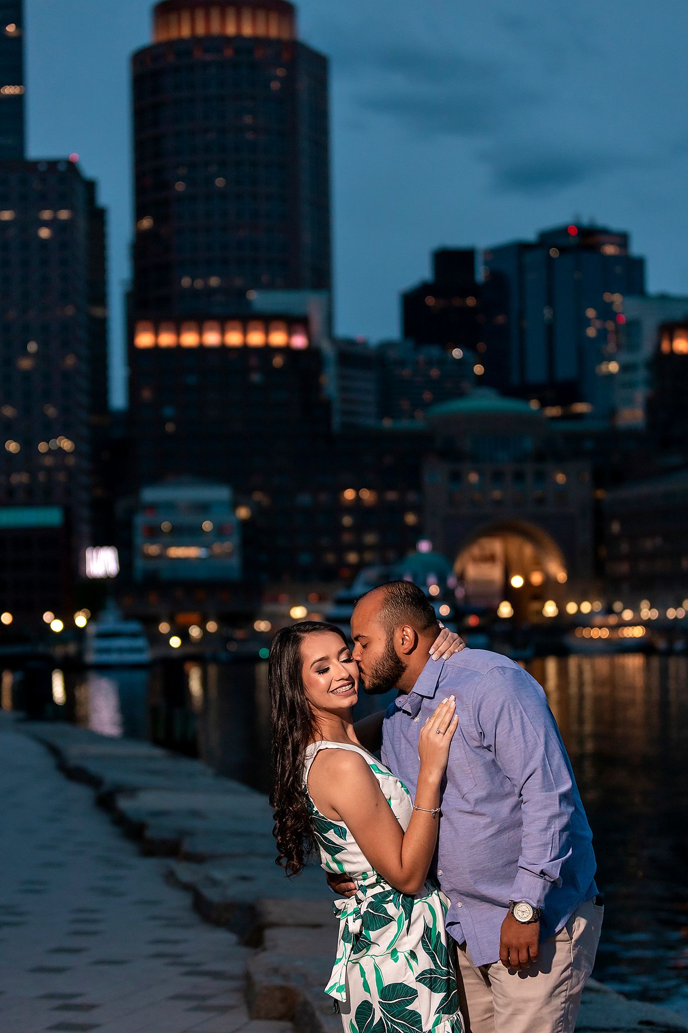 City skyline at dusk serves as backdrop for romantic couple's photoshoot.