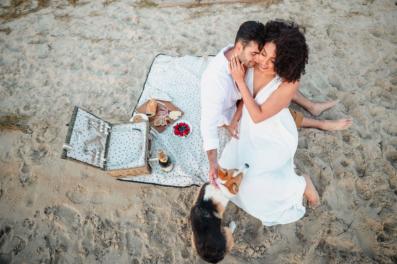 Couple lying on white blanket on beach sand.