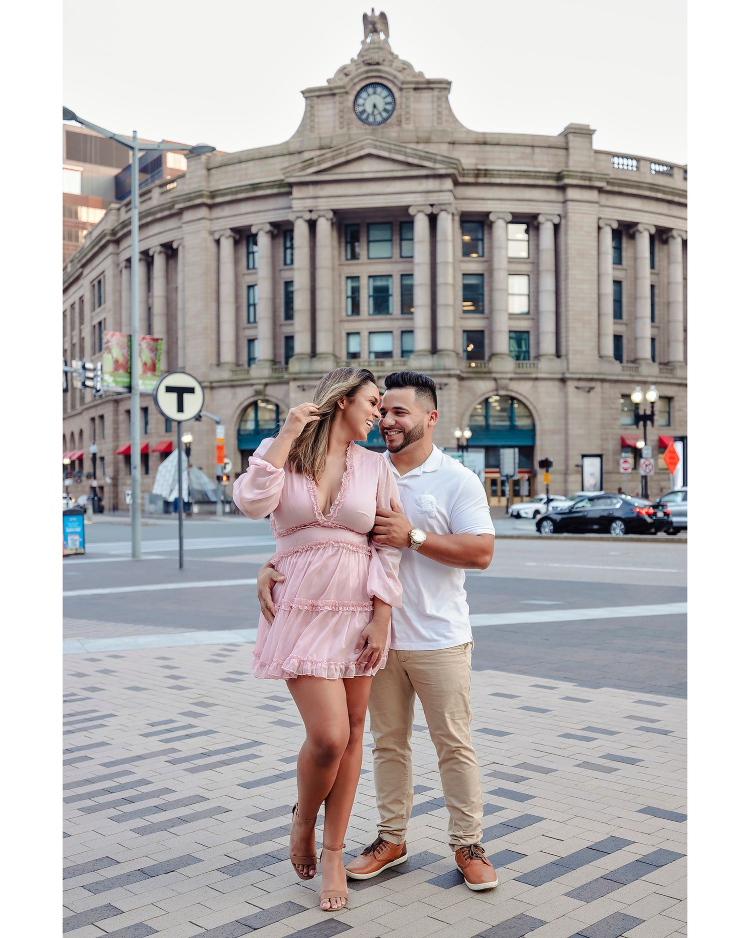 Couple dancing and posing in front of historic stone building with clock tower.