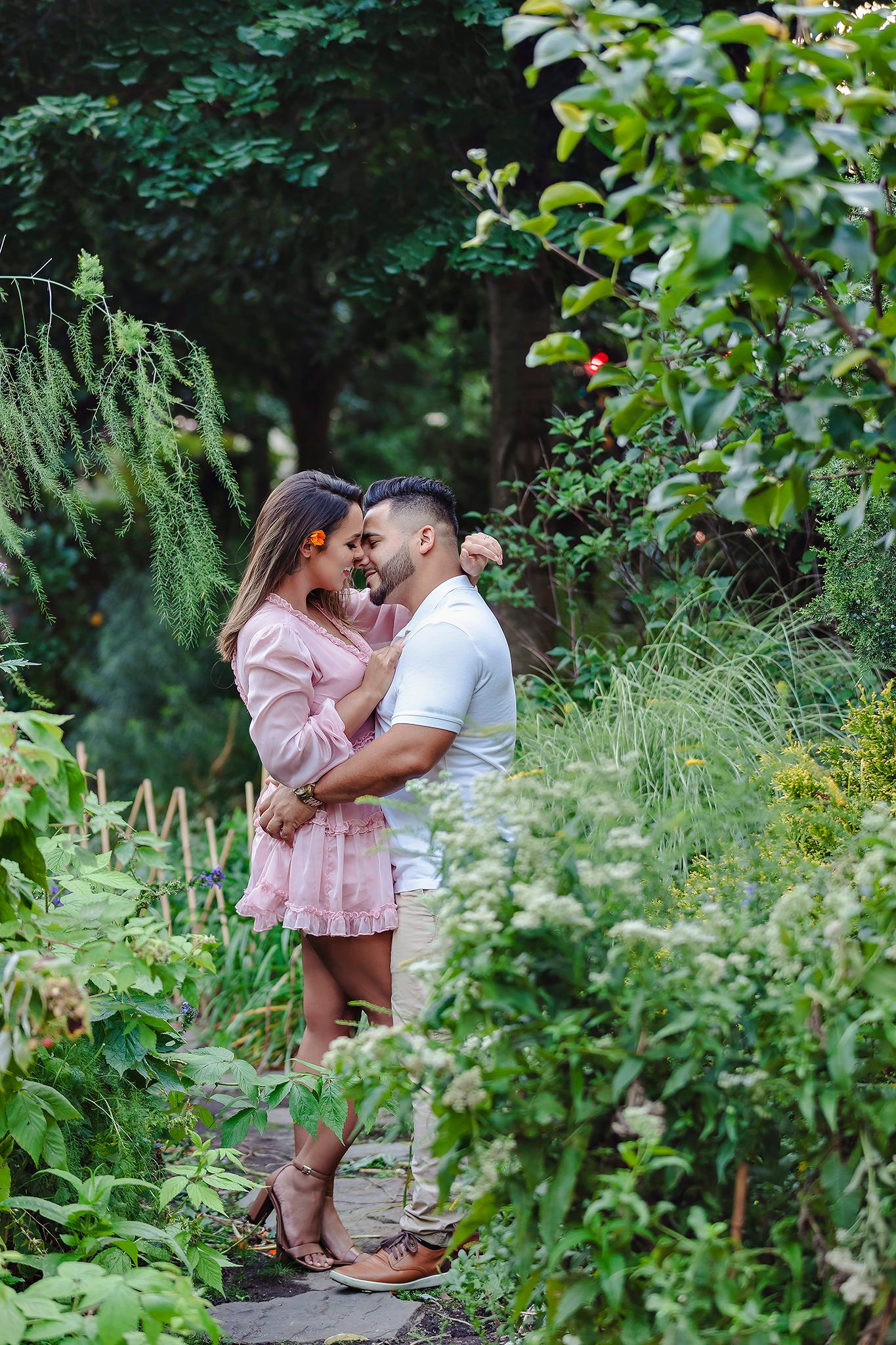 Romantic couple sharing intimate moment among lush garden greenery.