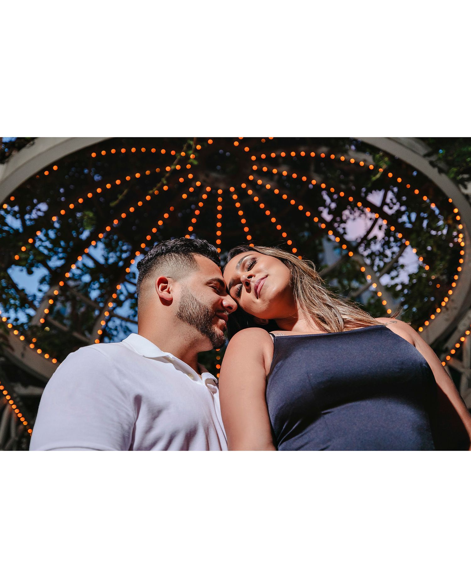 Romantic outdoor moment under string lights and gazebo at dusk.
