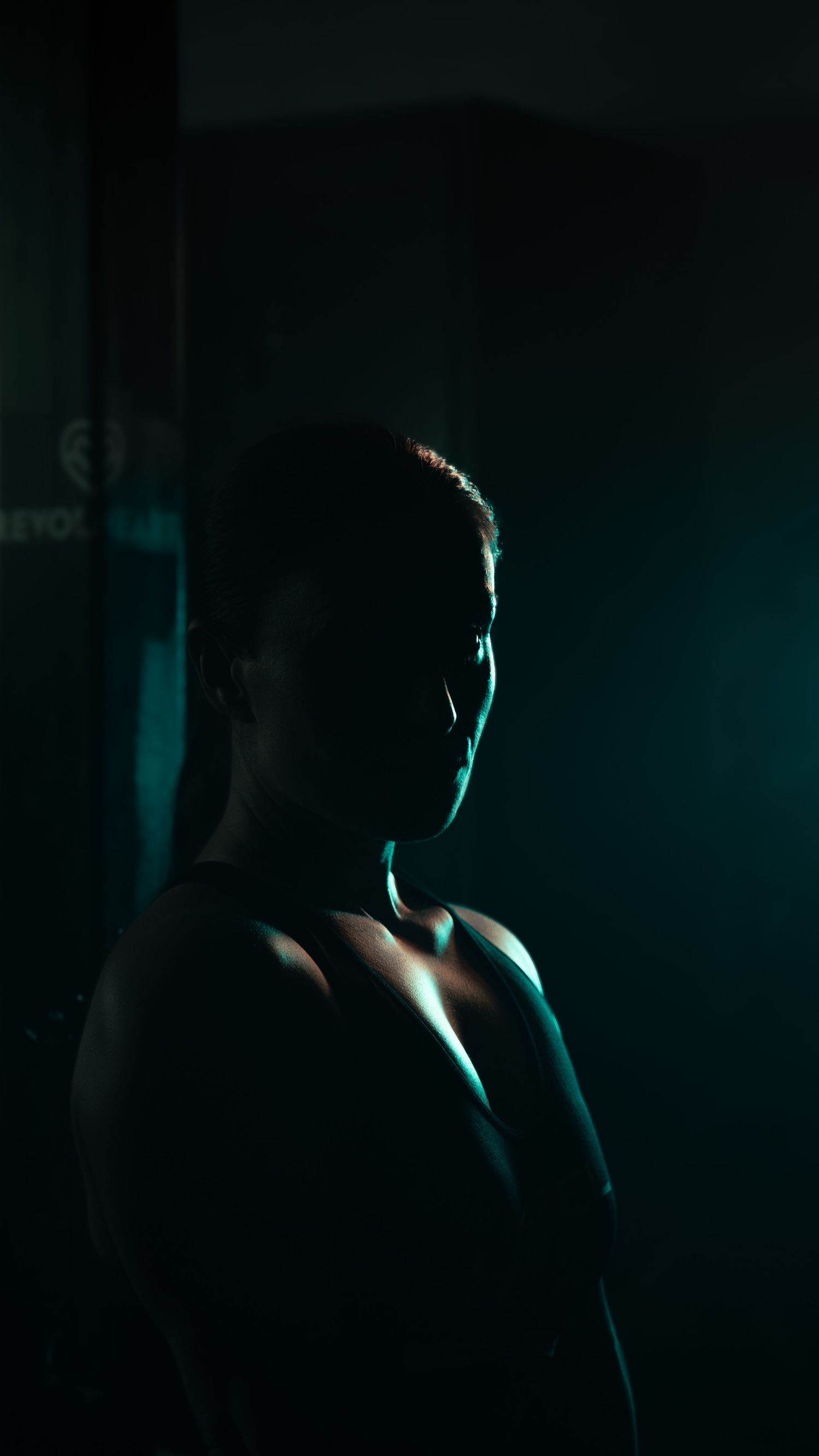 A dramatic side-lit silhouette of an athlete in a dark gym setting.