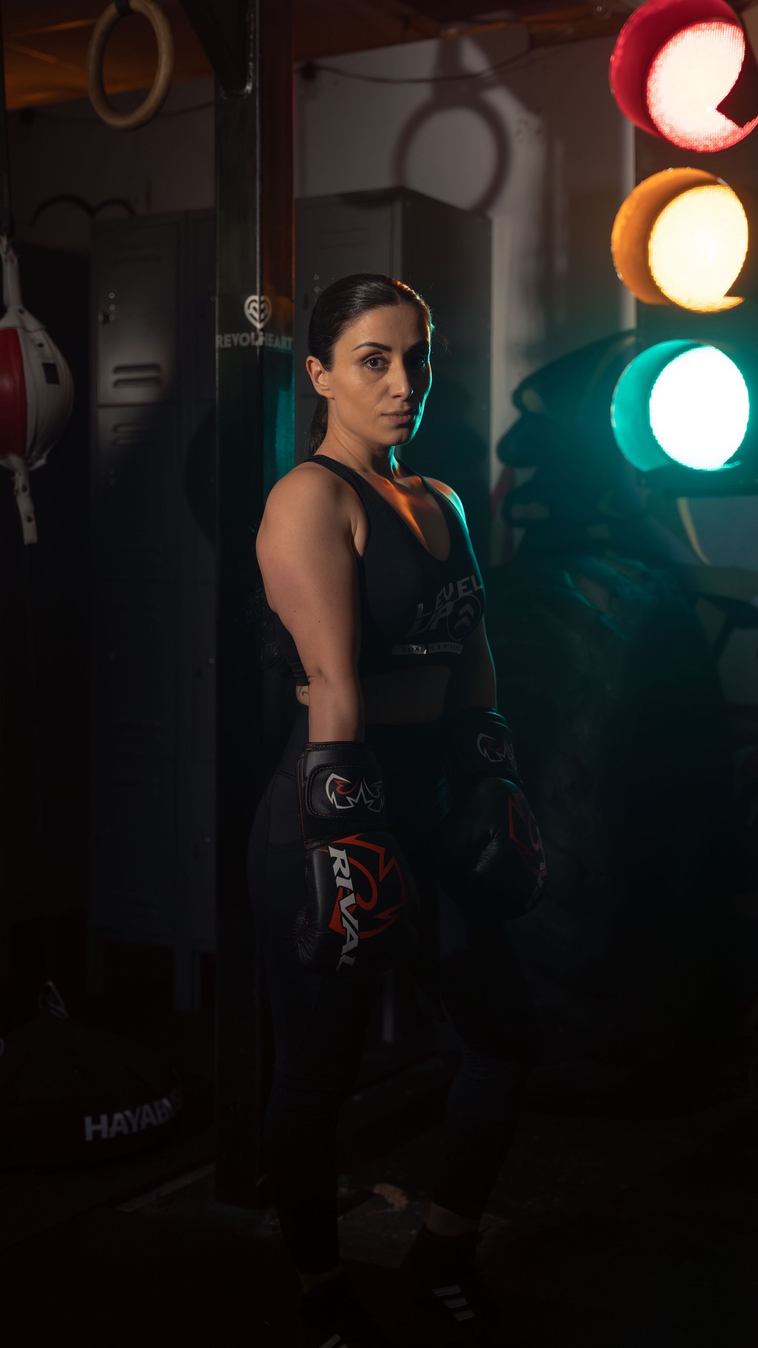 An athlete in boxing gear stands confidently against colorful gym lighting.