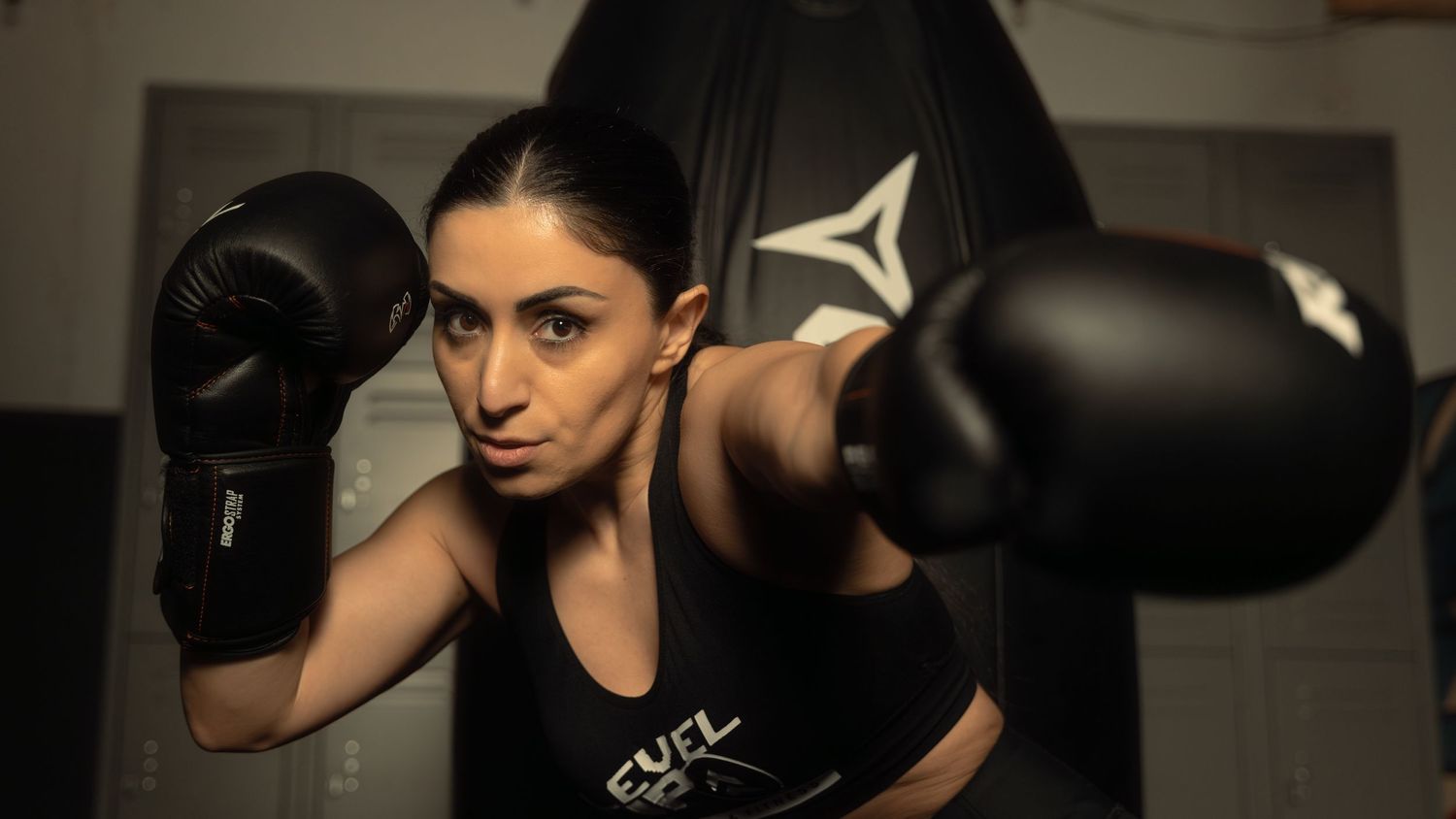 A boxer wearing black gloves and athletic wear throws punches during training.