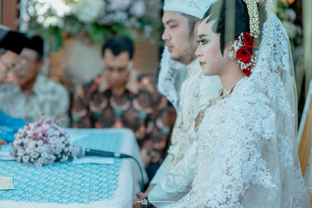 Traditional Javanese wedding ceremony with intricate white lace and cultural attire.