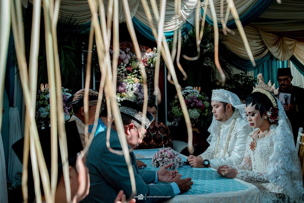 Wedding celebration with hanging decorations and traditional Indonesian formal wear.