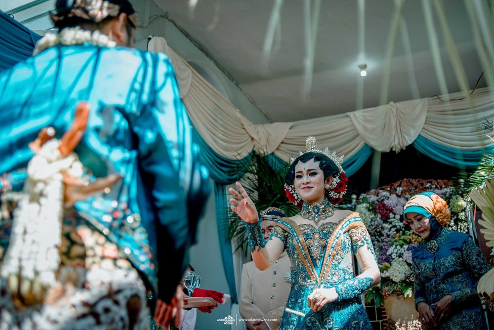Wedding celebration with turquoise decor and traditional Indonesian formal wear.