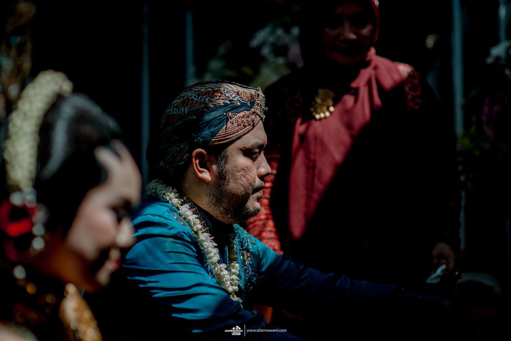 Traditional Javanese wedding ceremony participants wearing ornate blue and gold traditional clothing.
