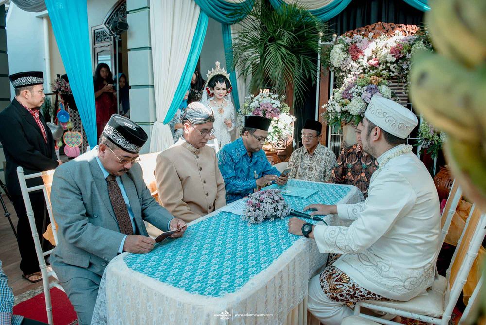 Traditional Indonesian wedding ceremony participants gathered around a table with turquoise decorations.