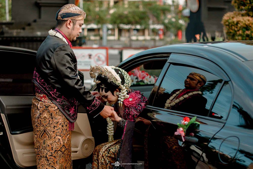 Traditional Indonesian wedding ceremony with couple in ornate attire entering vehicle.