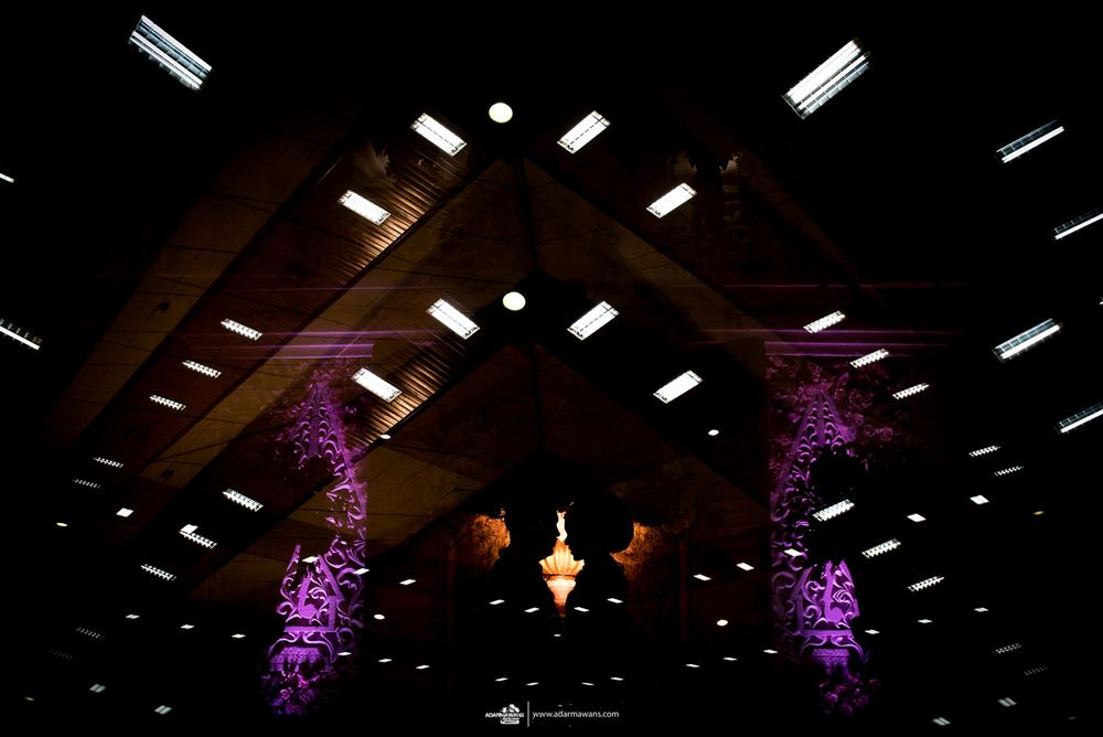 Dramatic lighting illuminates wedding venue with purple uplighting and hanging decorations.