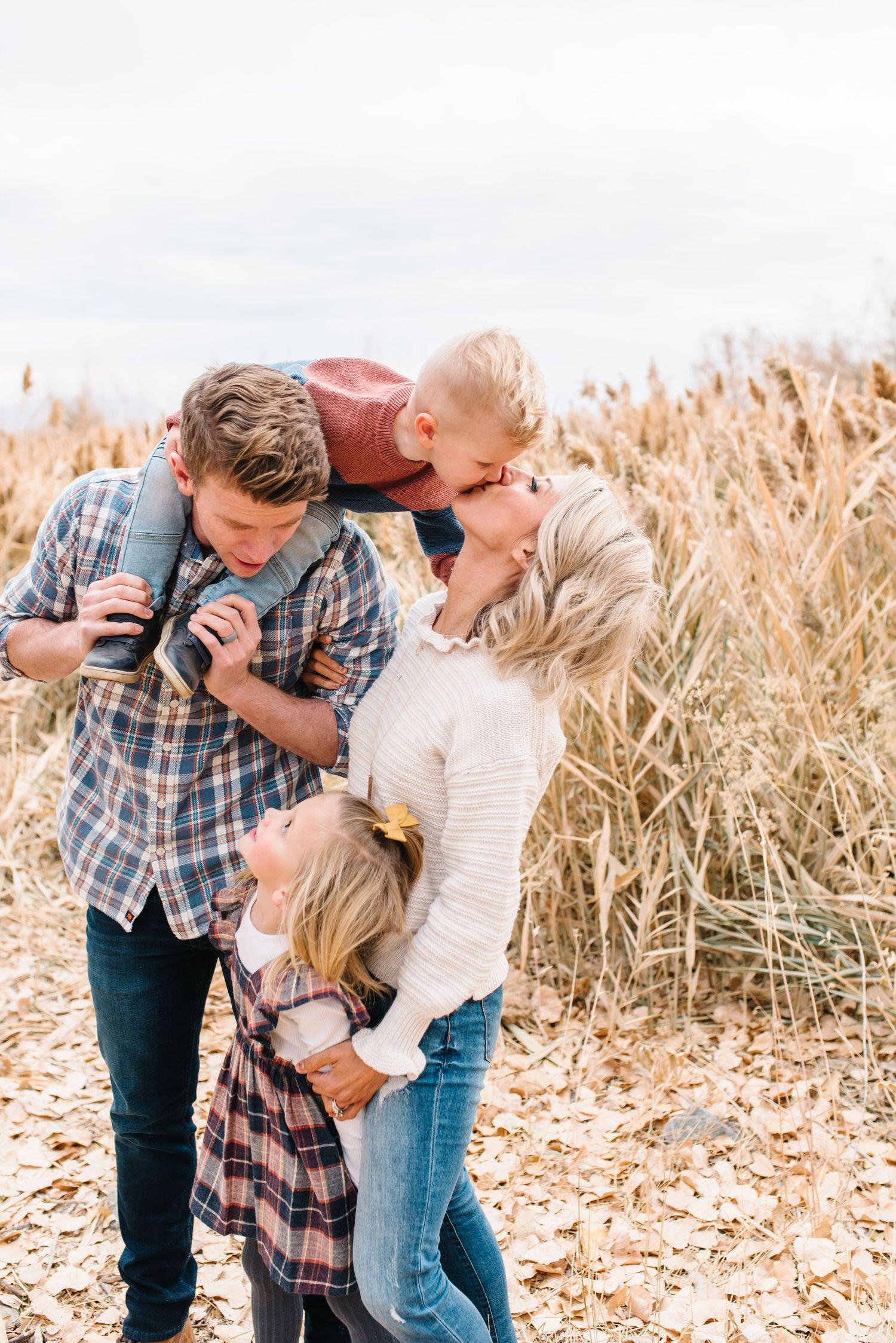 A loving family shares a candid moment together in a golden wheat field during sunset.