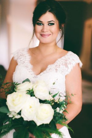 Classic bridal portrait with elegant lace dress and white rose bouquet.