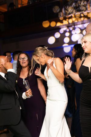Wedding reception guests enjoying a lively dance floor moment under ambient lighting.