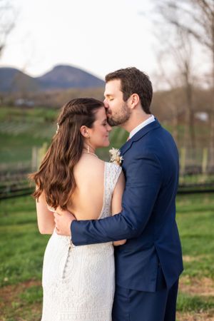 A tender intimate moment between newlyweds in a scenic outdoor setting with rolling hills.