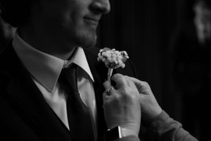 Close-up of a groom wearing a suit and boutonniere in black and white.