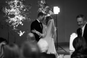 A black and white photo of a wedding ceremony with illuminated trees in the background.