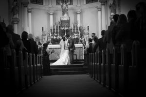 Black and white photograph of a church wedding ceremony with guests seated in wooden pews.