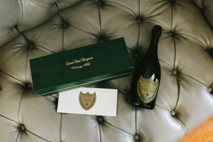 Luxury champagne bottle and gift box displayed on grey tufted leather surface.