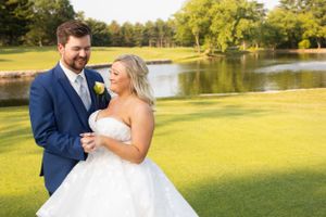 A wedding couple shares an intimate moment on a lush golf course with a lake in the background.