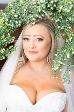 Bridal portrait framed by cascading greenery and small white flowers.