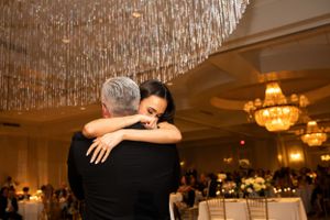 Intimate dance moment under crystal chandelier at elegant wedding reception.