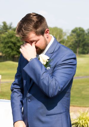An emotional moment captured as someone in a blue suit wipes their eyes during a wedding.