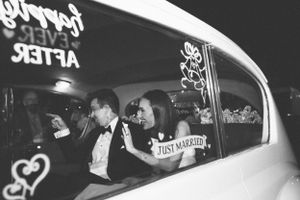 Newlyweds departing in a classic car with 'Just Married' written on the window.