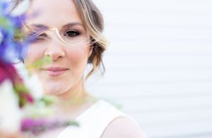 Soft focus portrait with purple flowers creating a dreamy bokeh effect in natural light.