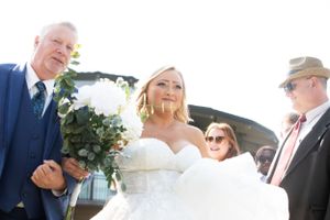 Outdoor wedding ceremony scene with white dress and formal attire.