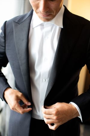 Close-up of formal black tuxedo with crisp white shirt being buttoned.