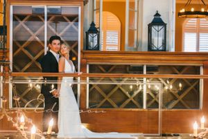 A romantic wedding portrait against wooden paneling with lantern decorations and warm lighting.