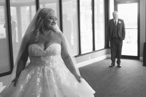 A heartwarming first look moment captured in black and white at a sunlit indoor venue.