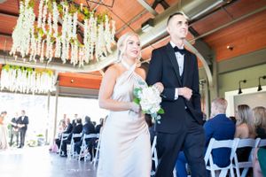 Happy couple walking down the aisle under hanging floral decorations.