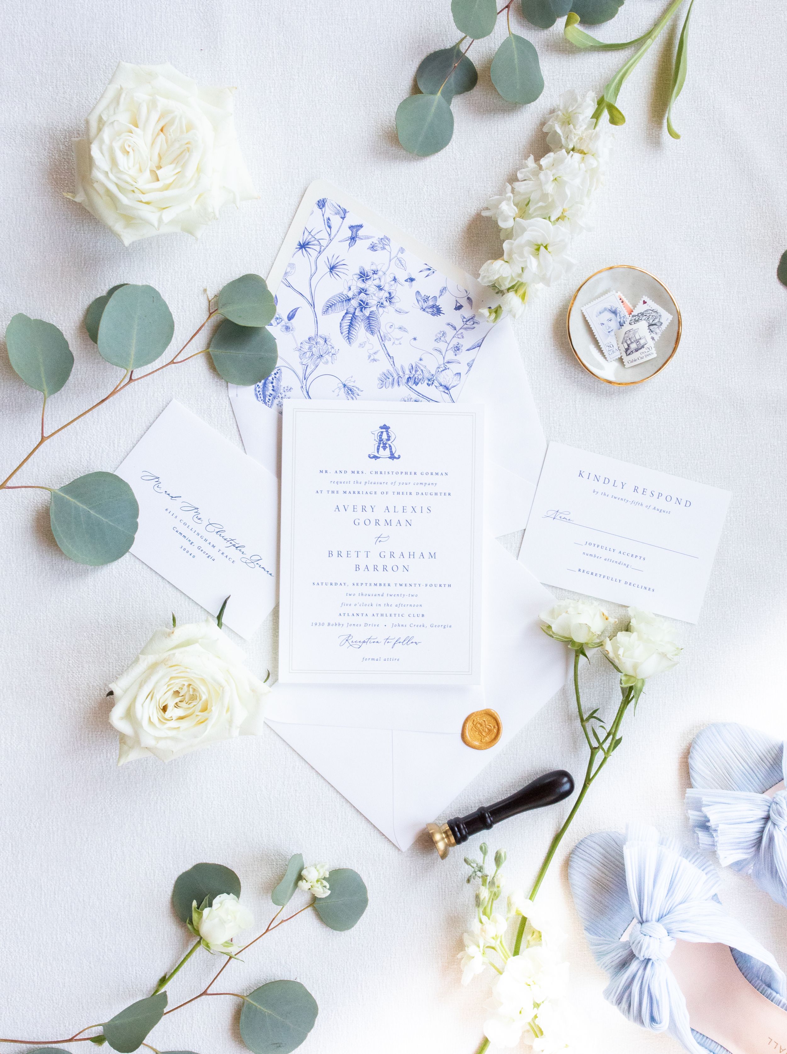 Elegant wedding invitation suite with white roses and eucalyptus on white background.