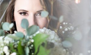 A bridal portrait softly focused behind romantic greenery and white flowers.